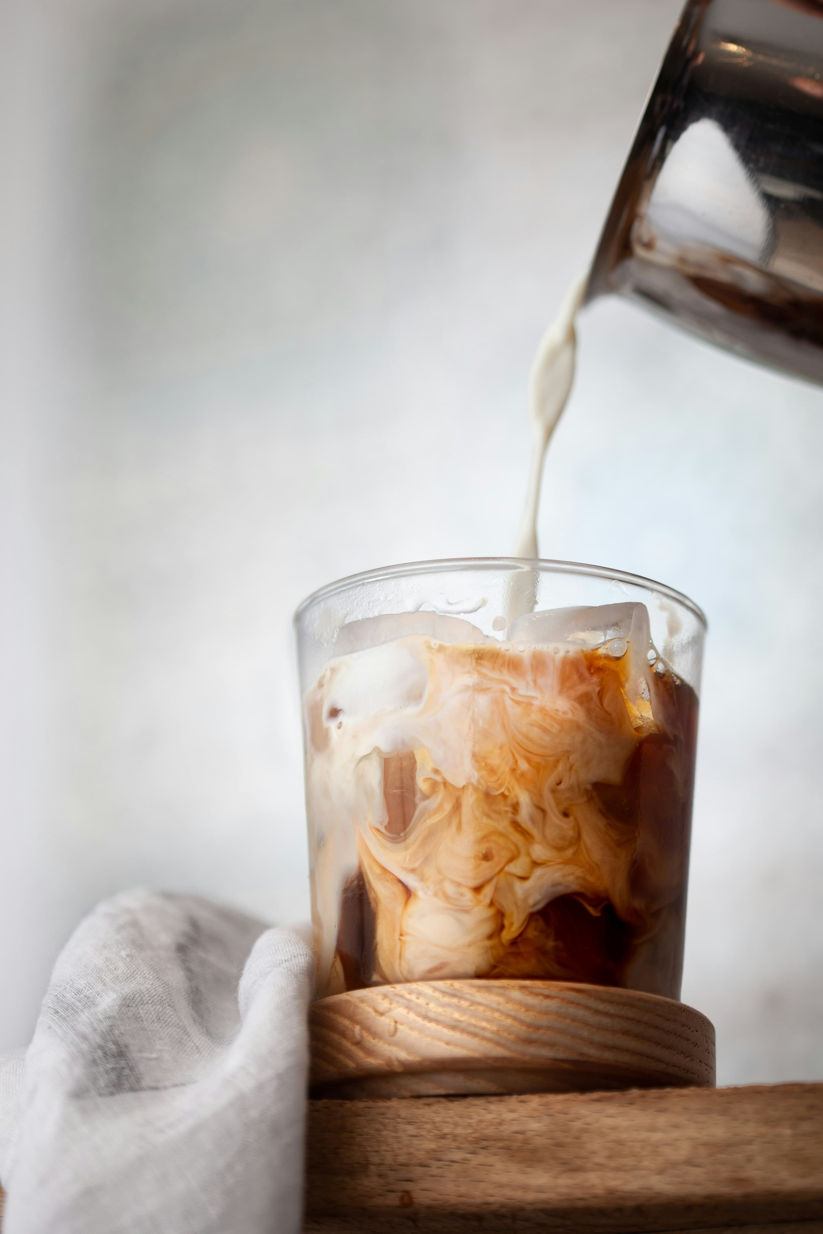An ice coffee being poured into a glass